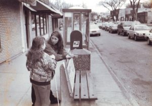 Woman with white cane waiting at bus stop with instructor