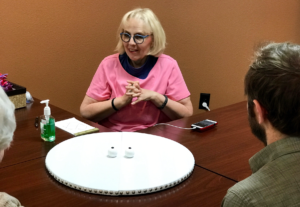 Linda in conversation, a tactile work of art is on the table in front of her